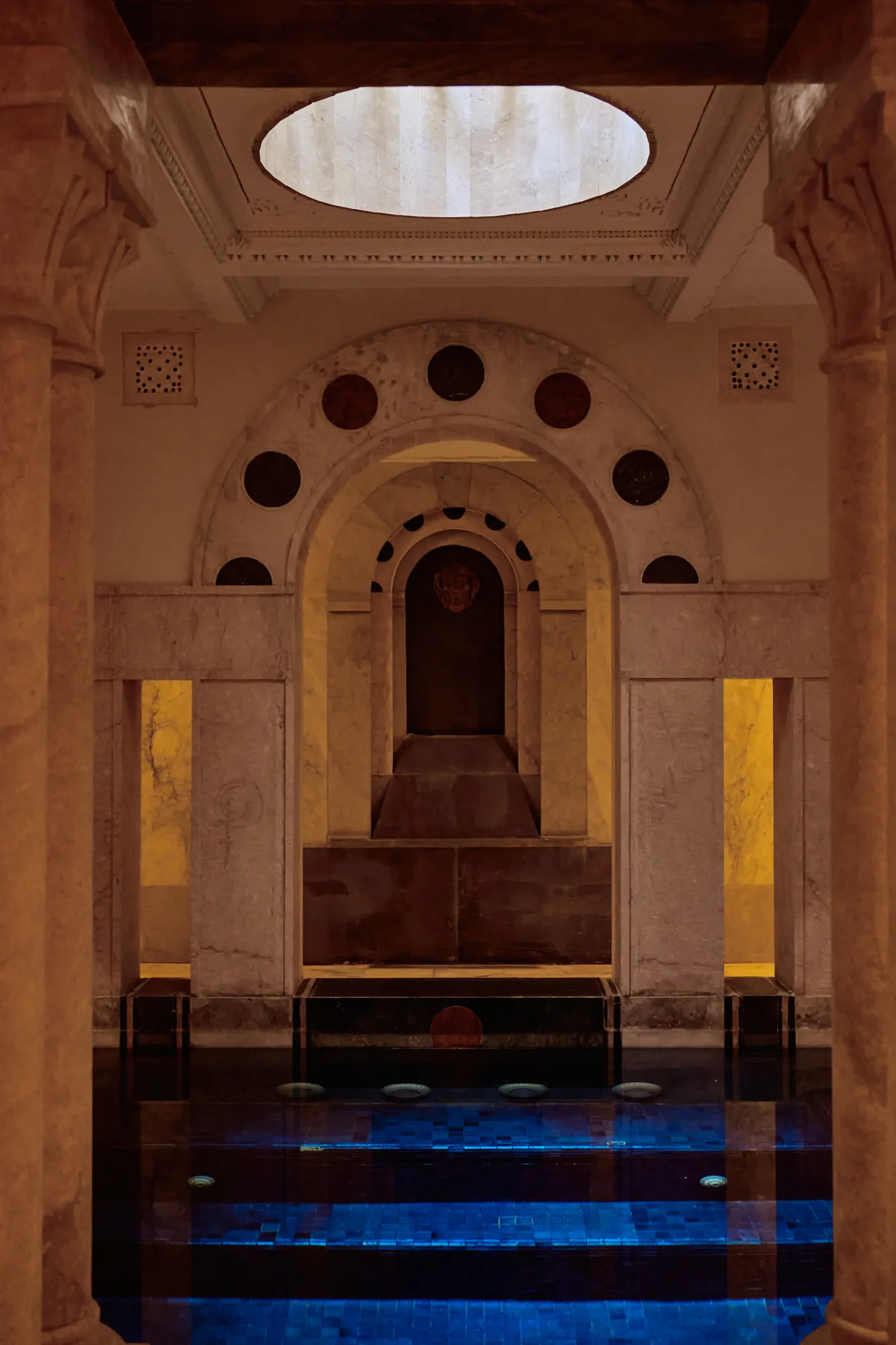 The dome of the hammam above steps descending into blue water.