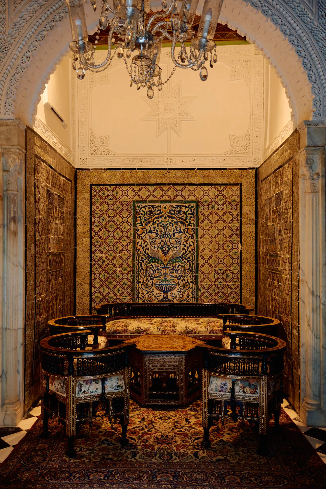 A tiled salon with a round banquette and a woven carpet.