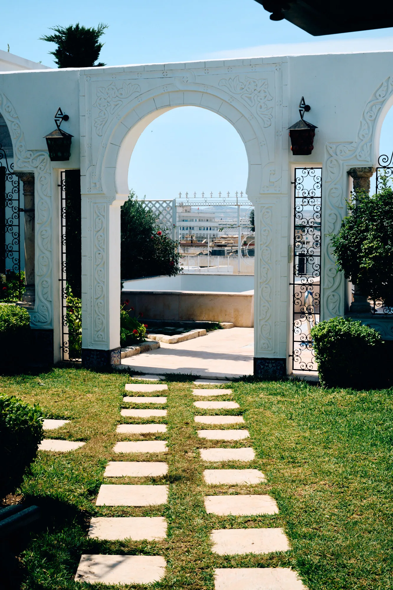 A path of stone slabs crossing the garden towards a white arch.