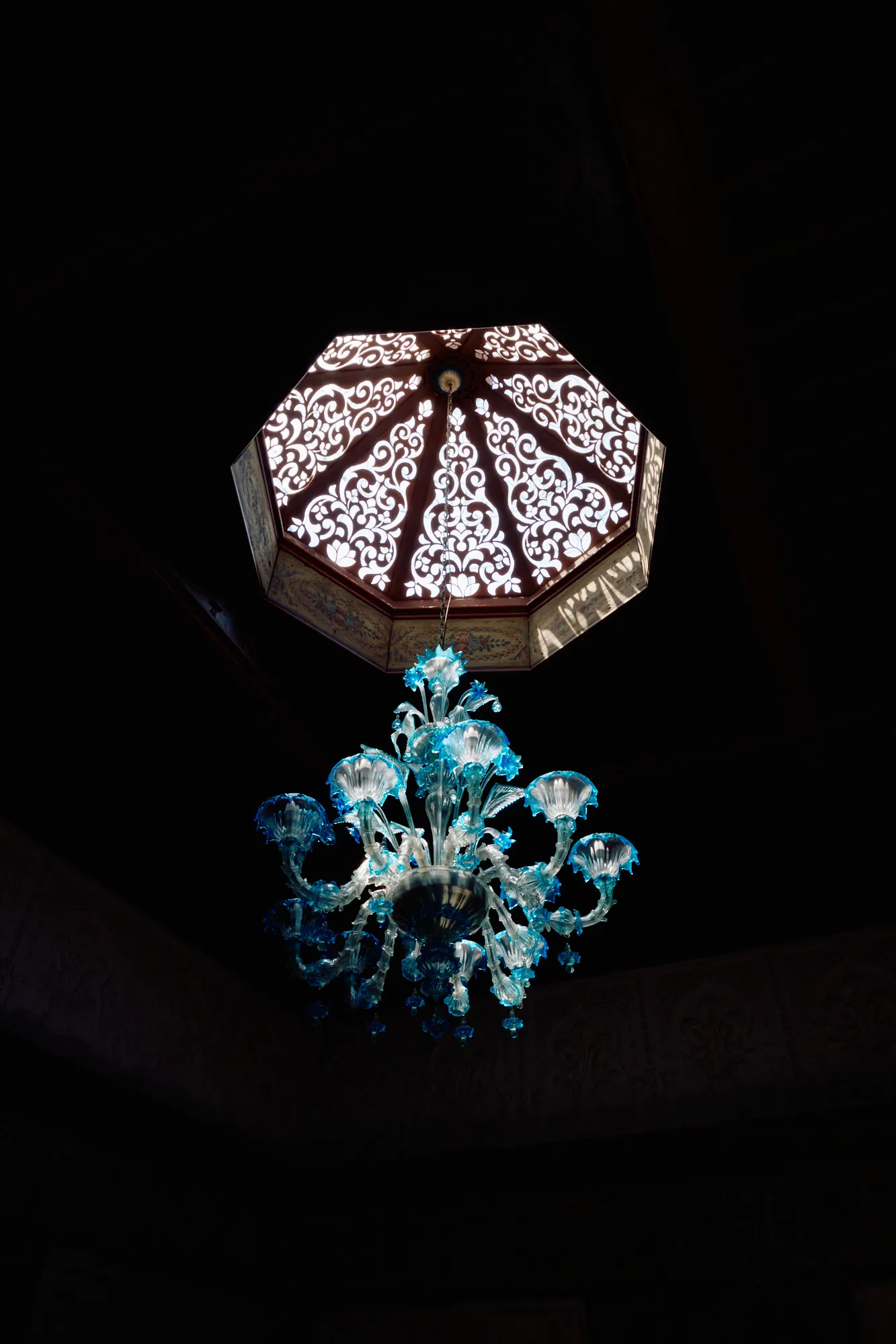 A pierced dome above a chandelier of turquoise glass.