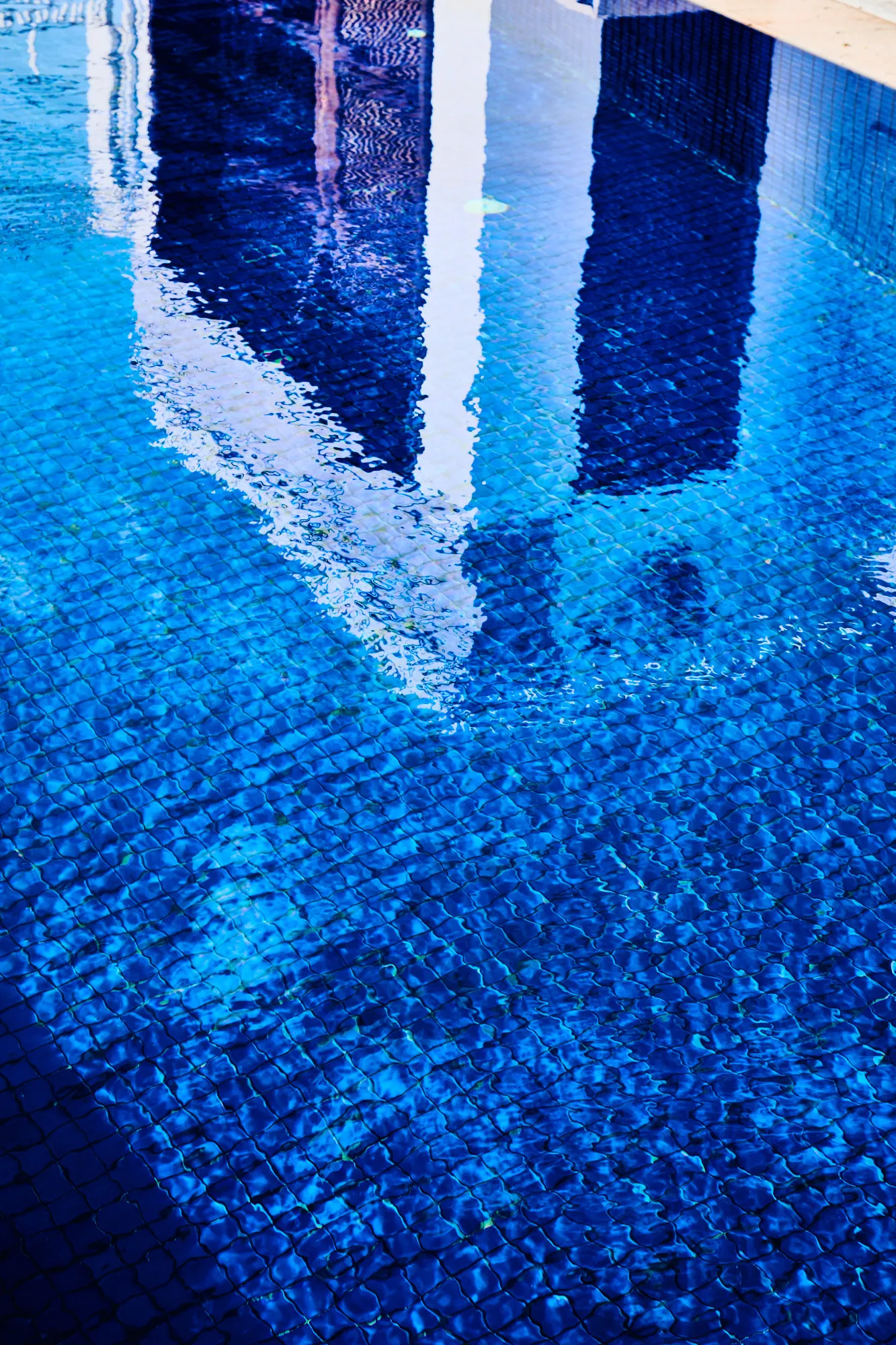A reflection breaking across the blue water of the pool.