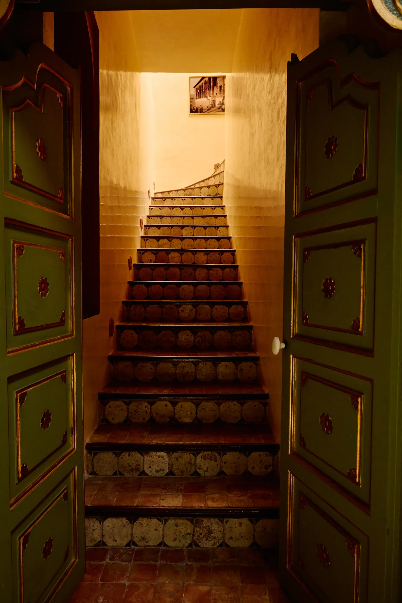 A staircase climbing away behind an open green door.