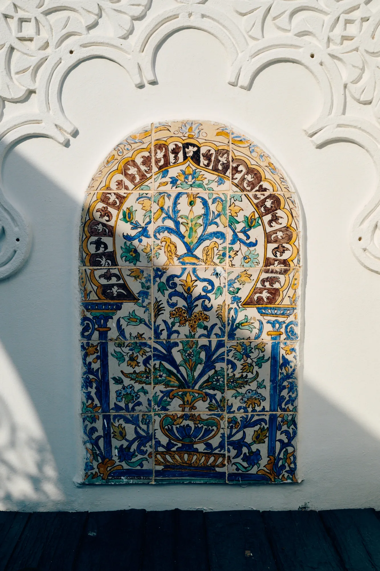 A tiled niche set into carved white plaster.