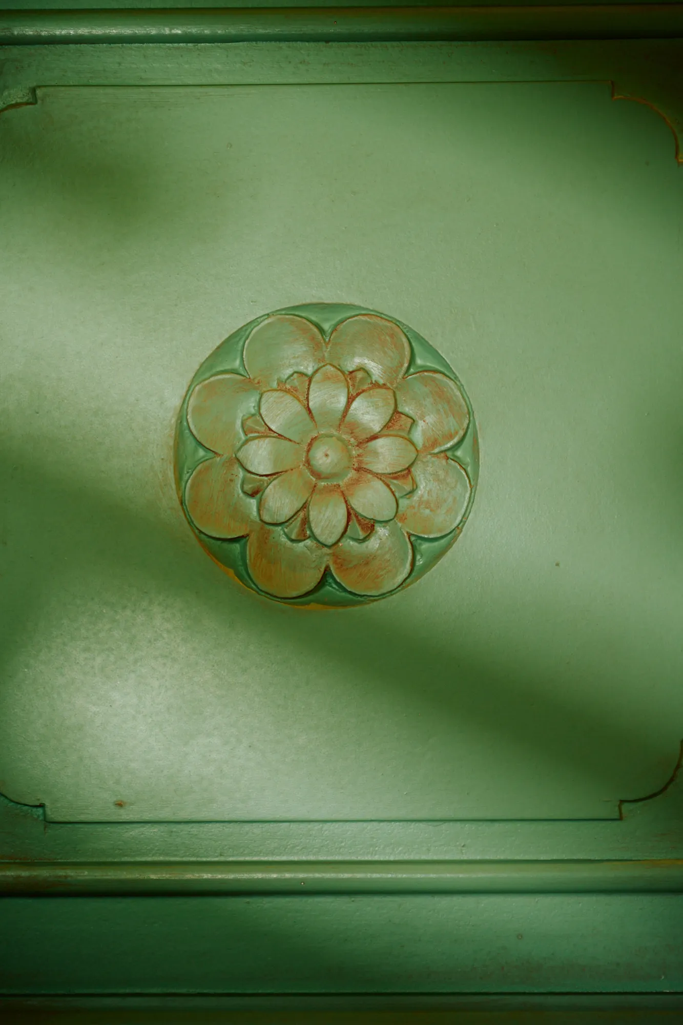 A gilded rosette on a green painted door.