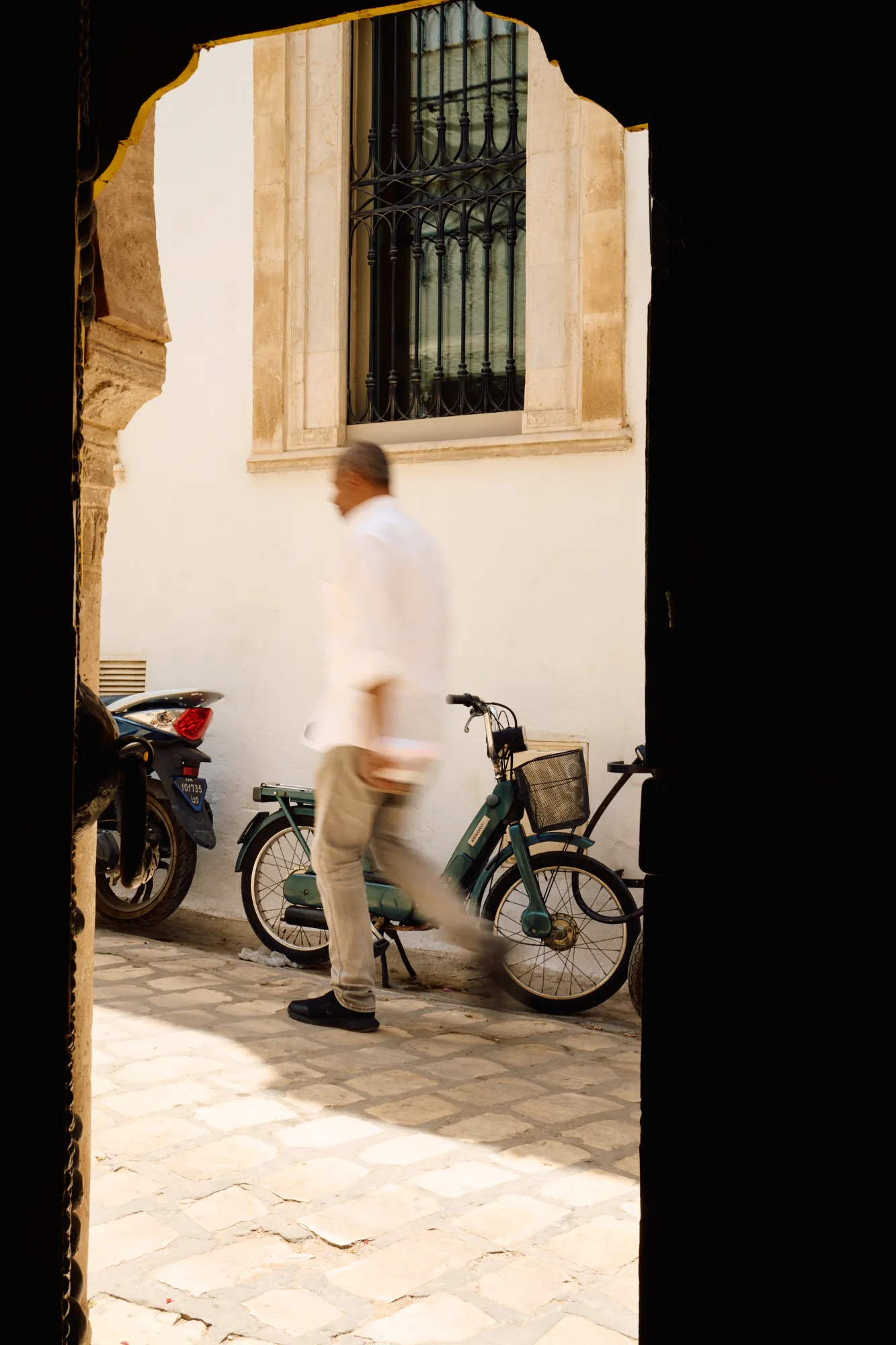 A figure passing in the alley, seen from inside the arch.