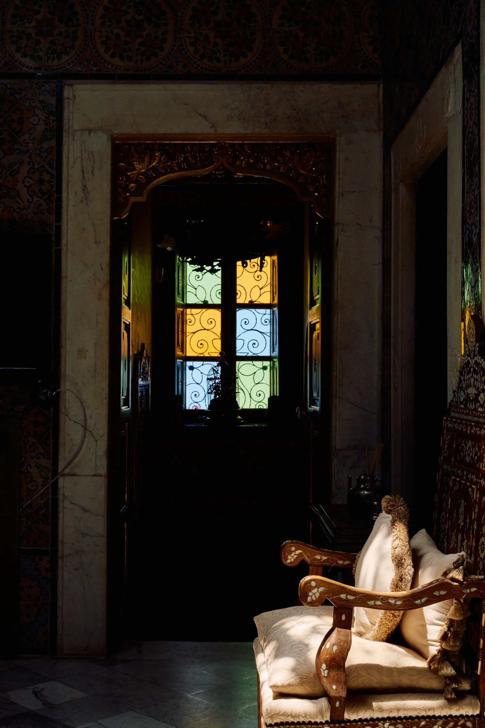 Light through a star-shaped stained-glass window, and a chair beneath it.