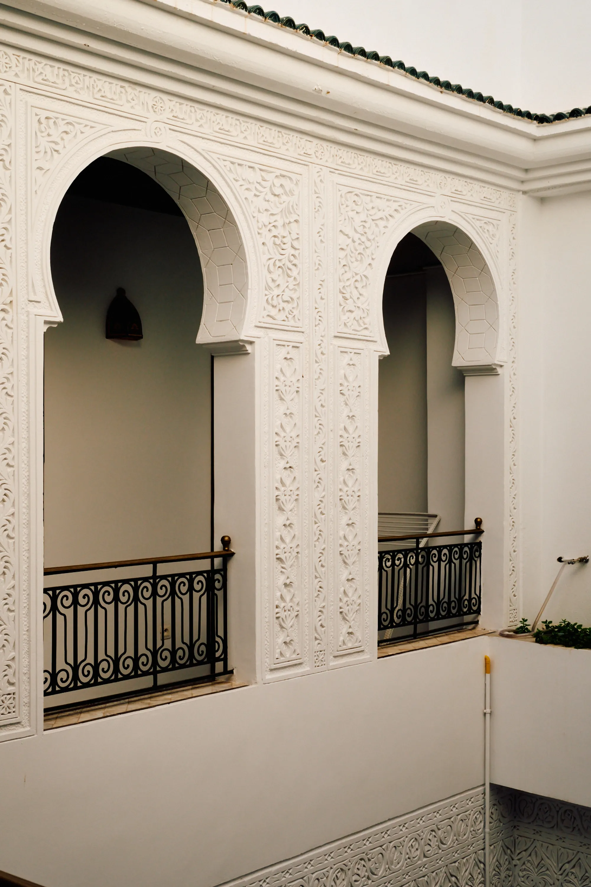An upper gallery of carved white arches above an iron balustrade.