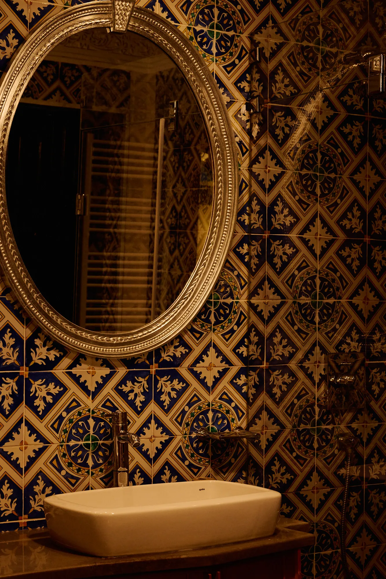 A bathroom in blue tilework with a stone basin.