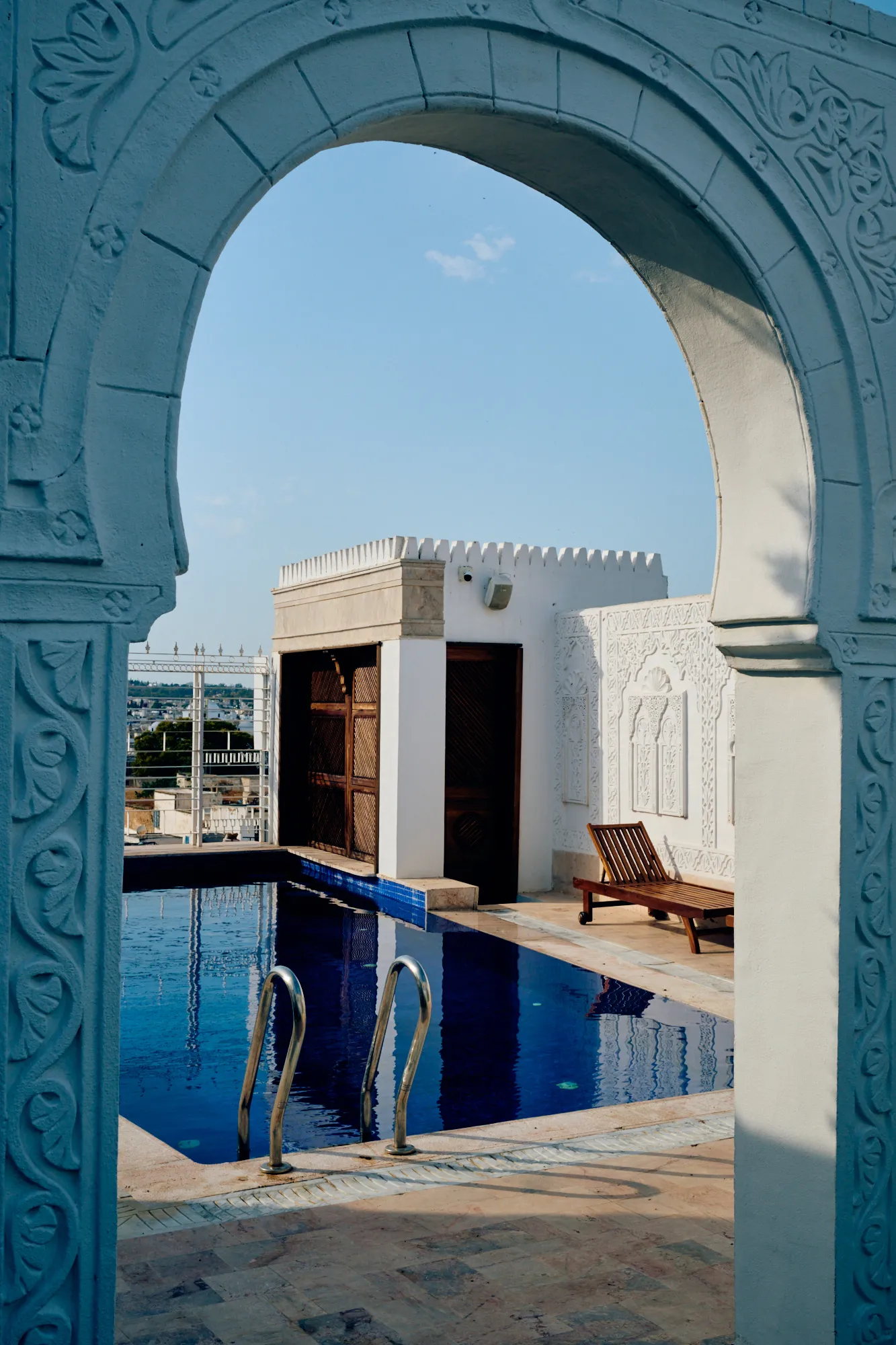 A blue carved arch opening onto the rooftop pool.