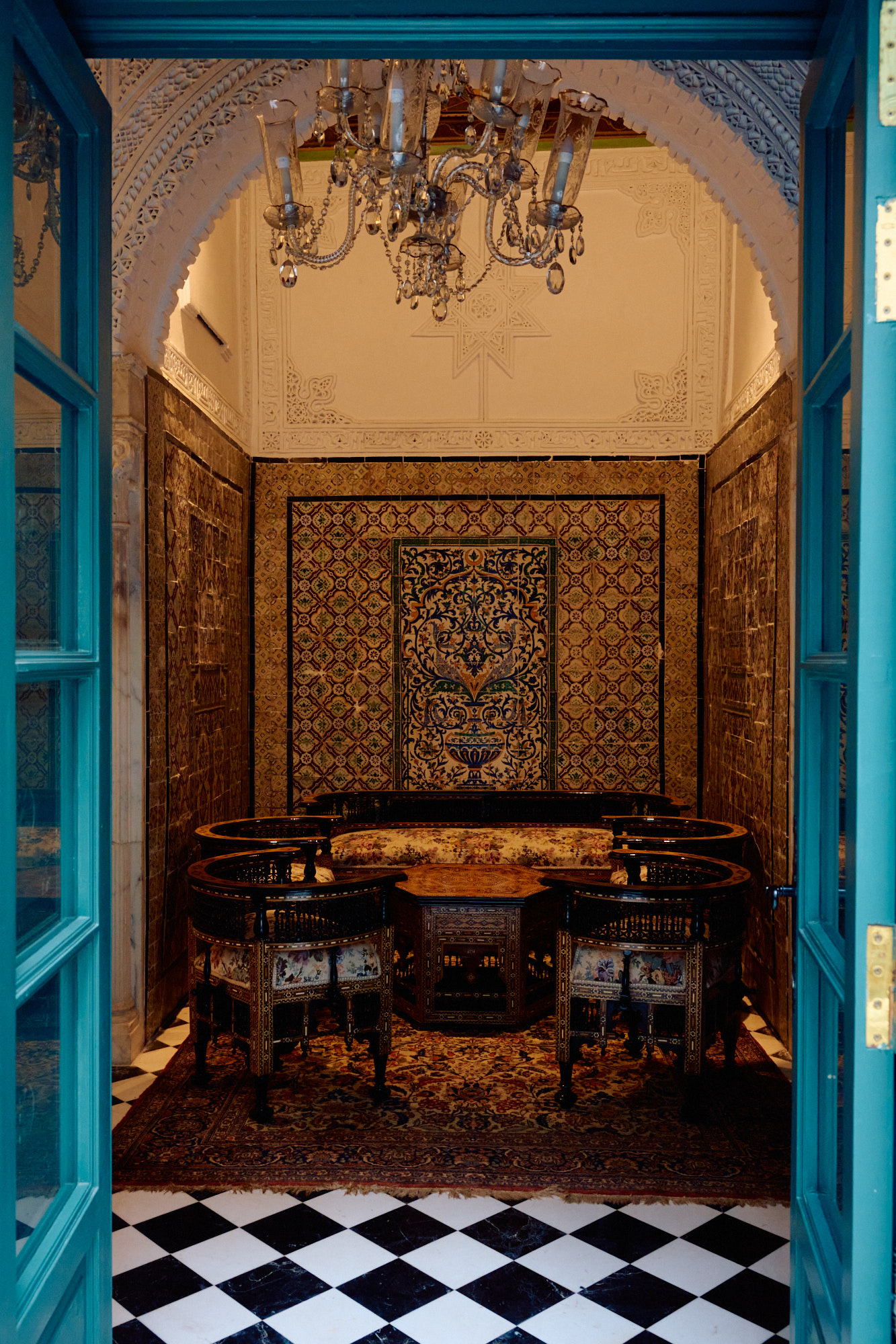 Des portes peintes en bleu, ouvertes sur une salle de faïence.