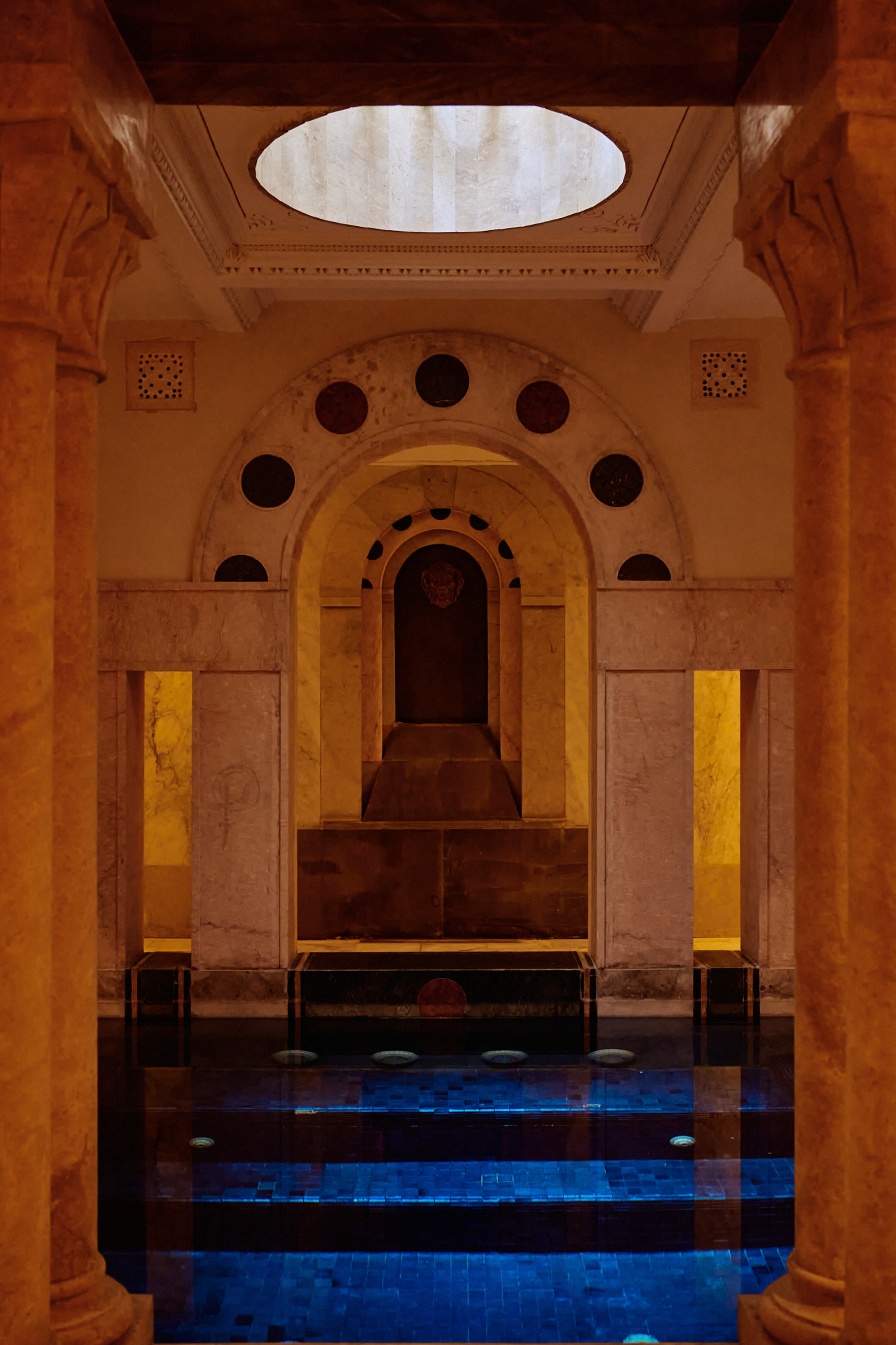 Le hammam du Palais Nour : une coupole ovale, une arche de marbre, et des marches qui descendent dans l'eau bleue.