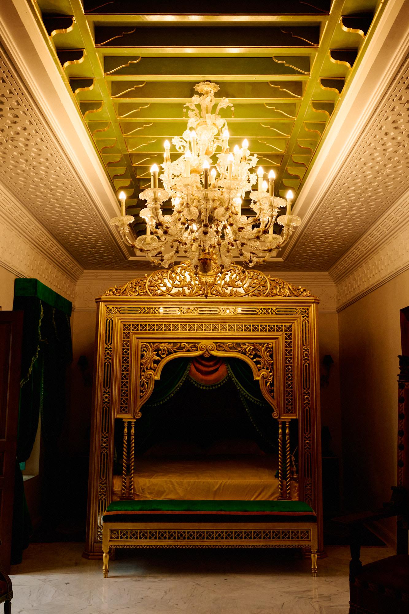 Un plafond peint de vert et d'or, et un lustre de cristal.