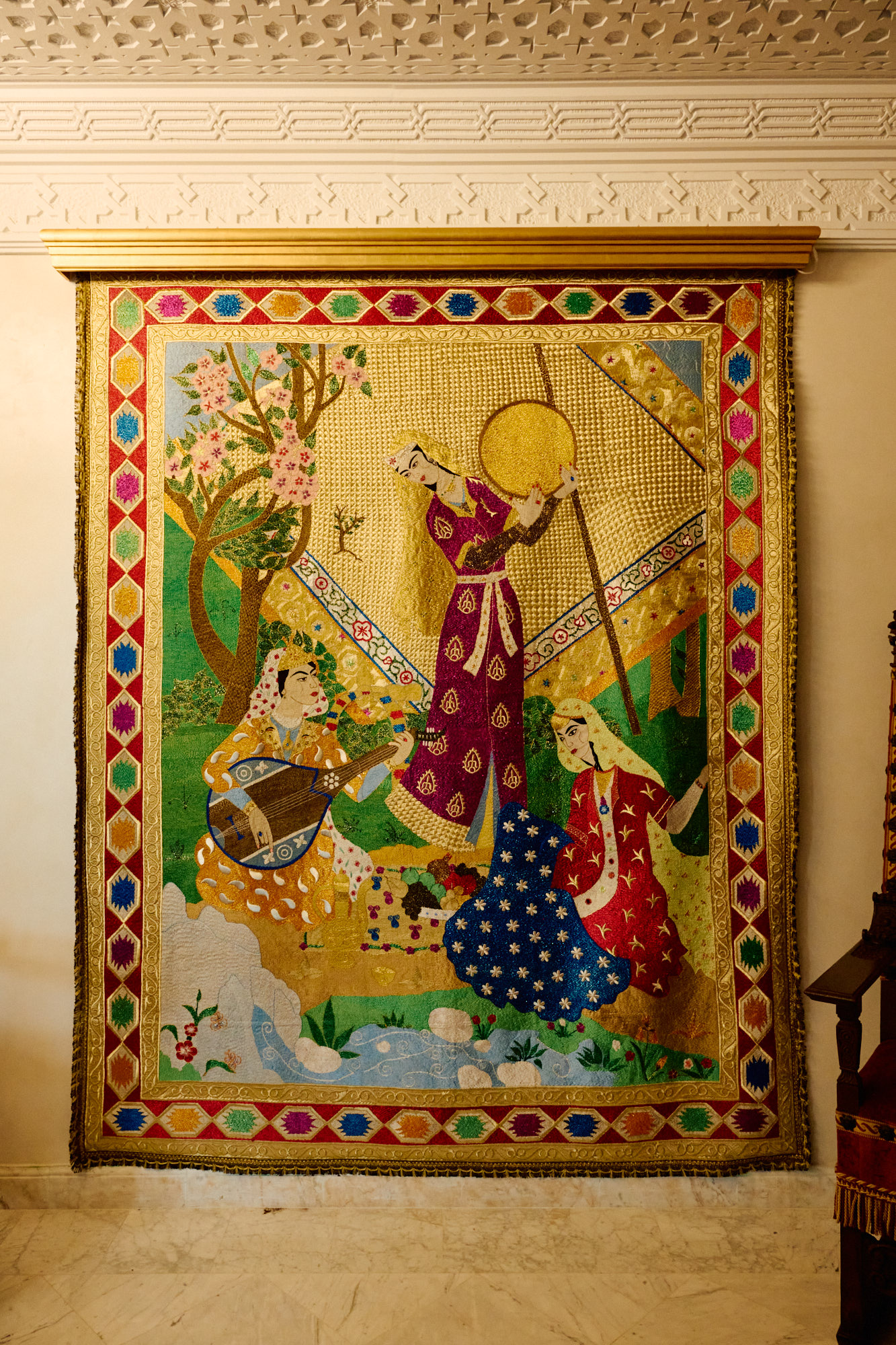 Une grande œuvre encadrée, aux musiciennes, sur un mur de plâtre blanc.